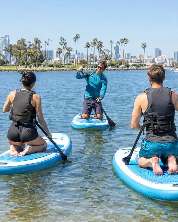 A beginner stand up paddle boarder learning in the shallow cove