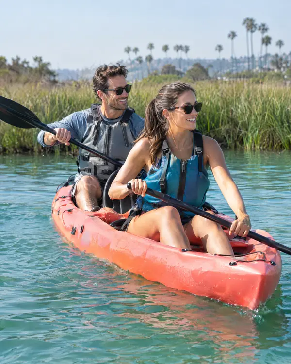 Couple paddling a tandem kayak on calm bay water